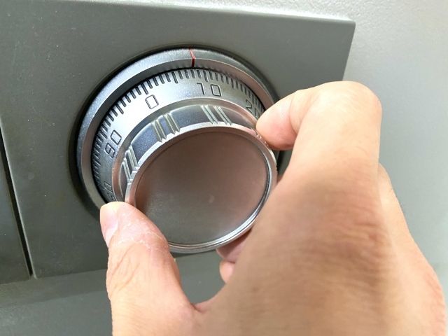 ダイヤル式金庫の番号を合わせて開錠操作をしている手元の様子。金庫の暗証番号確認や開錠作業をイメージした画像。